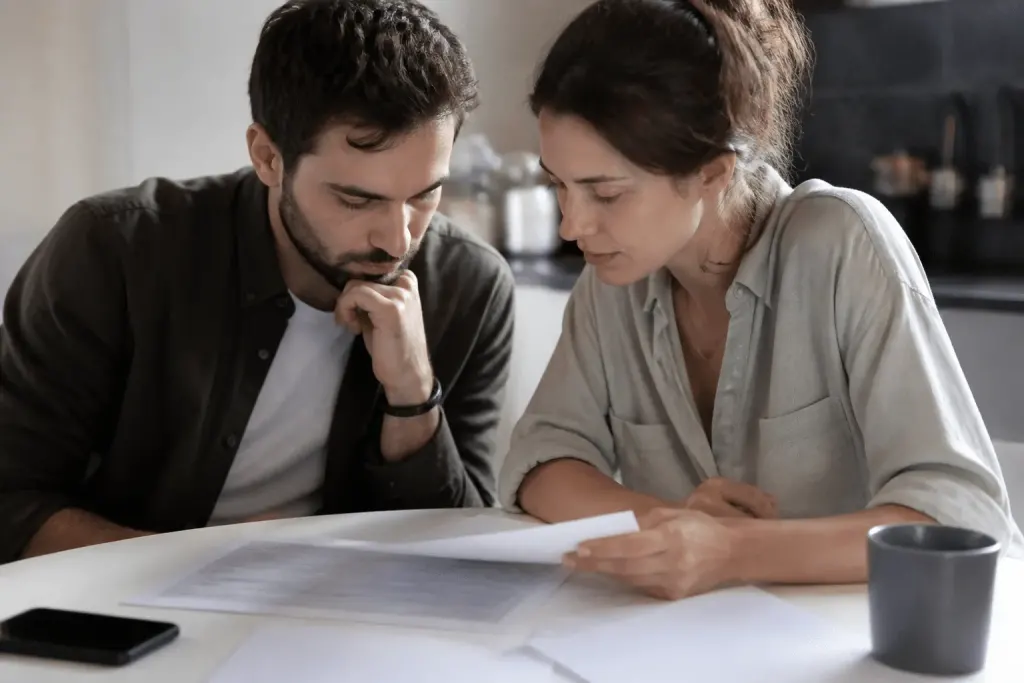 Couple consultant documents fiscaux sur table blanche