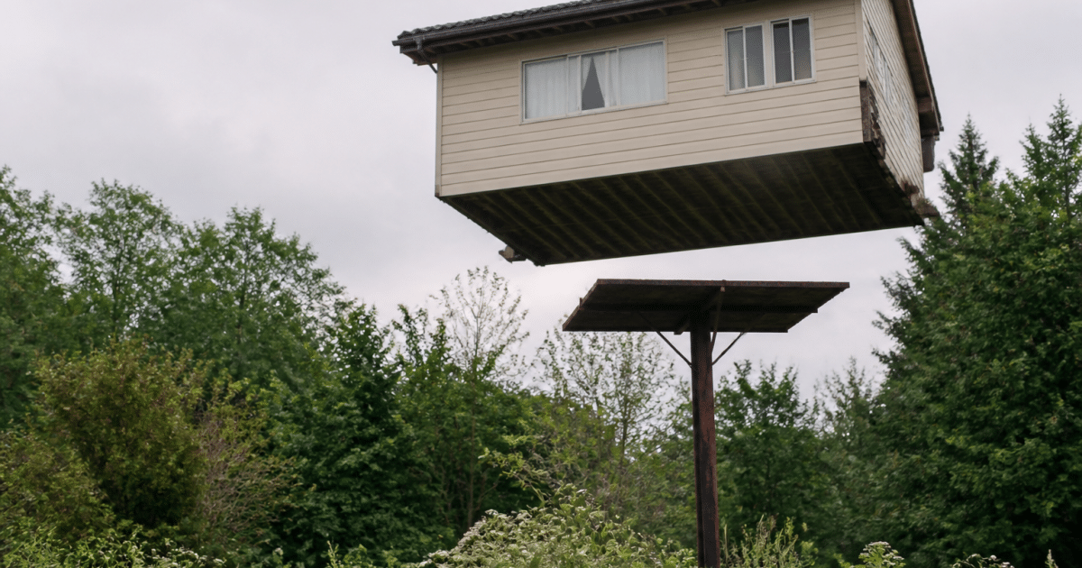 Maison suspendue au-dessus d'un panneau vendu immobilier