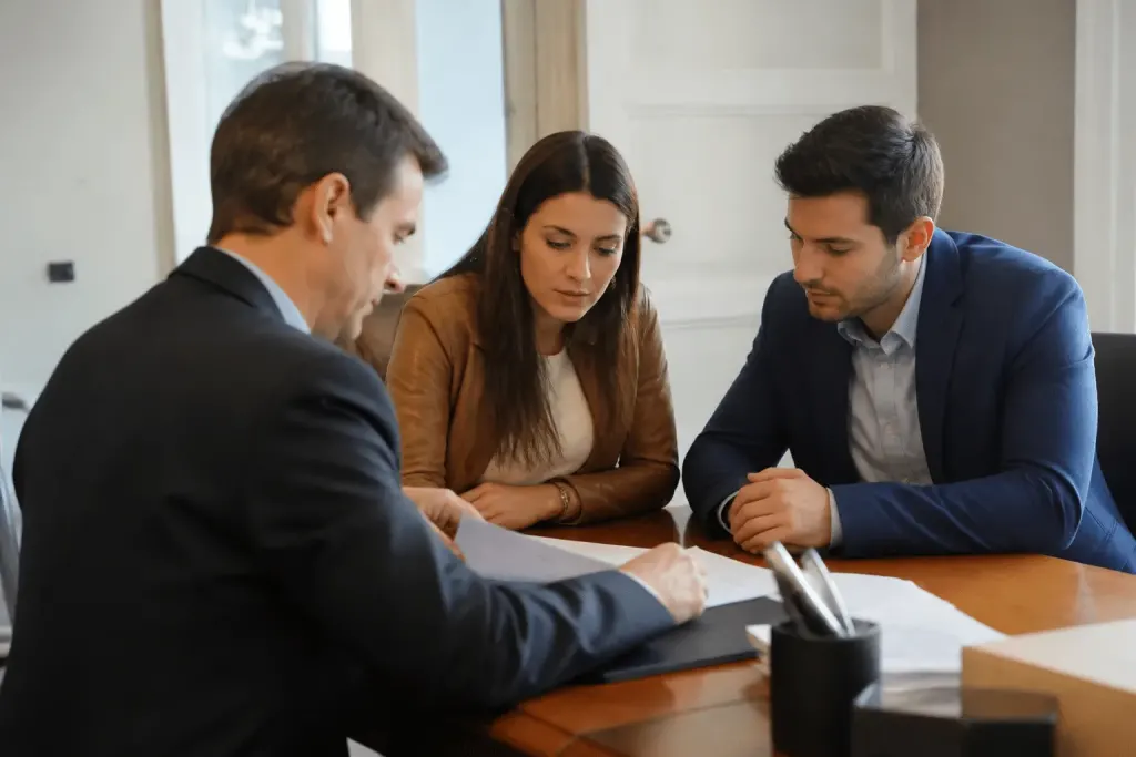 Notaire examinant documents immobiliers avec couple assis