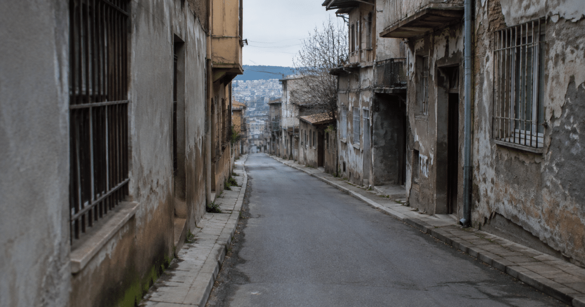 Rue déserte de quartier urbain avec immeubles délabrés et murs gris