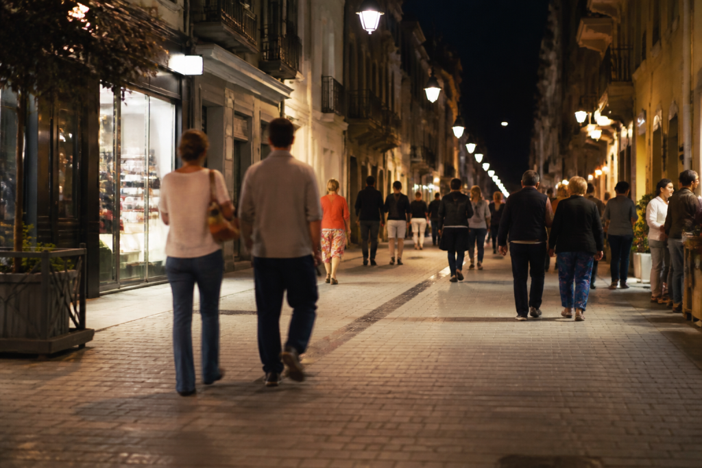 Rue eclairee la nuit avec commerces et passants