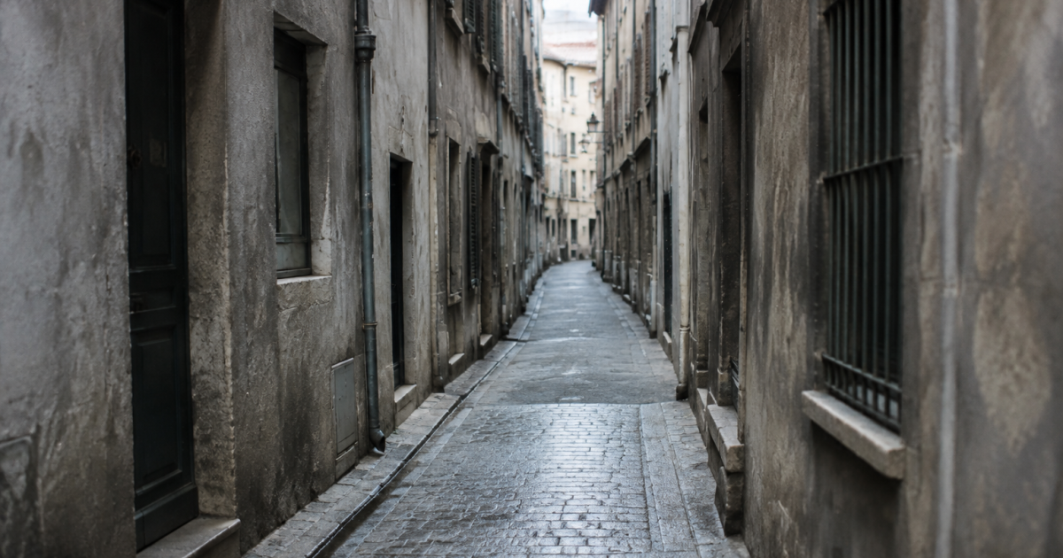 Rue etroite entre immeubles gris aux facades degradees