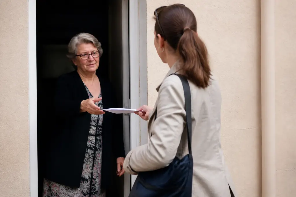 Agent recenseur remet questionnaire papier devant immeuble