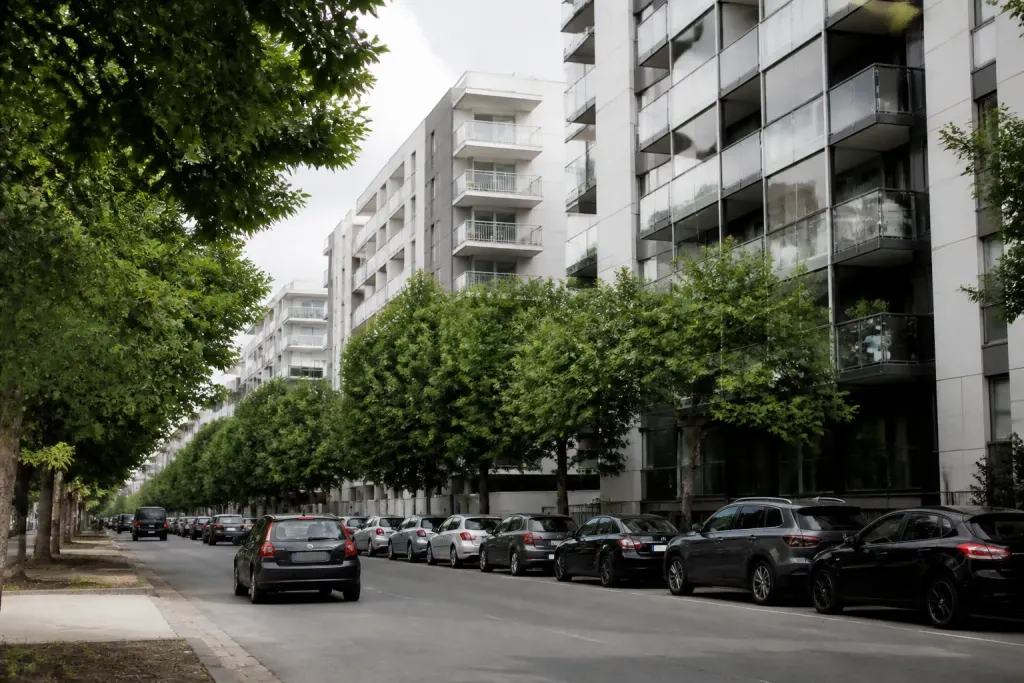 Immeubles modernes bordant une avenue arbree avec voitures