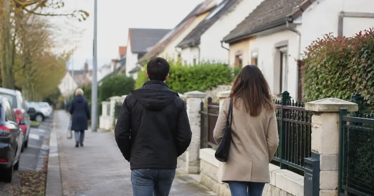 Passants marchant sur un trottoir borde de pavillons